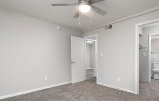 A room with a ceiling fan and carpeted floor.