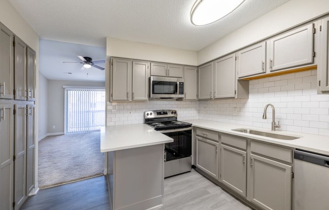 an empty kitchen with white cabinets and stainless steel appliances