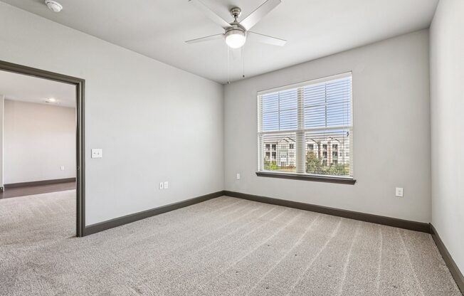 A room with a ceiling fan and a window with blinds.