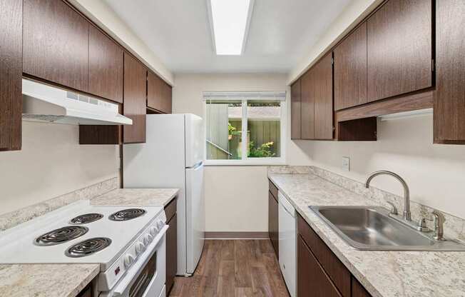 A kitchen with white appliances and brown cabinets.