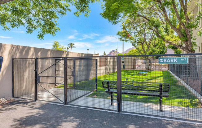 a gate to a park with a bench and a fence