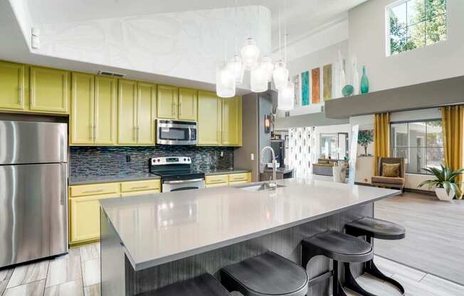 A modern kitchen with a stainless steel refrigerator and a central island with three stools.