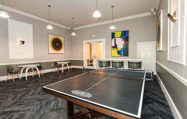 a ping pong table in a room with chairs and paintings