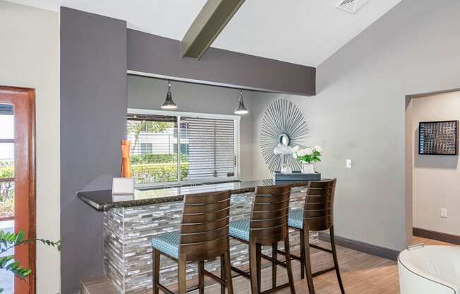 a bar with four chairs in a living room with a window