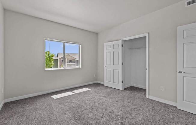 A room with a large window and a view of a house outside.
