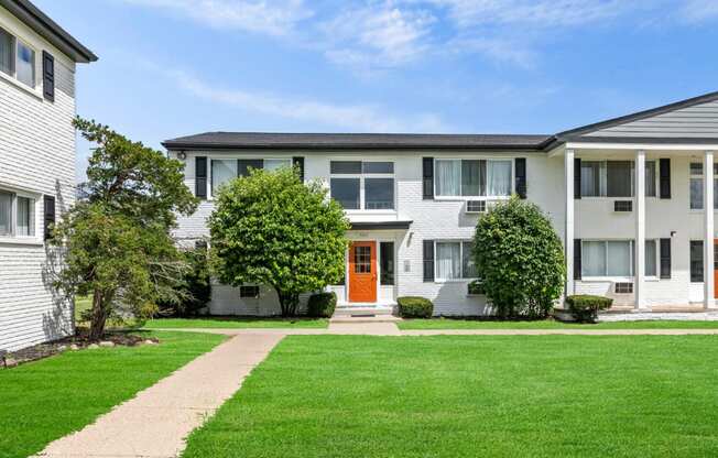 the view of an apartment building with a green lawn and a orange door