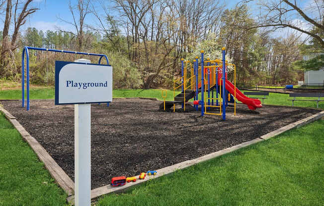 A playground with a red slide and a blue sign.