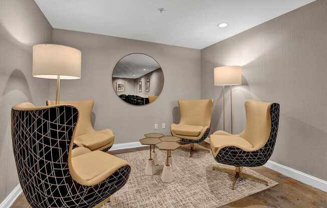 A living room with a black chair and a round mirror on the wall.