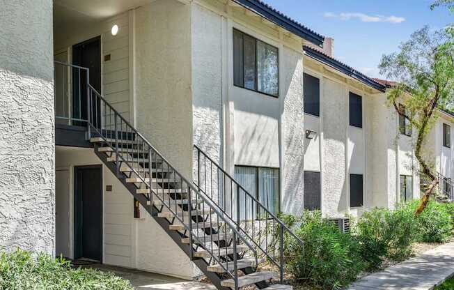 A white building with a black door and a metal staircase.