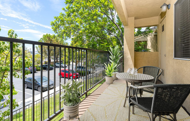 an apartment balcony with a table and chairs and a fence