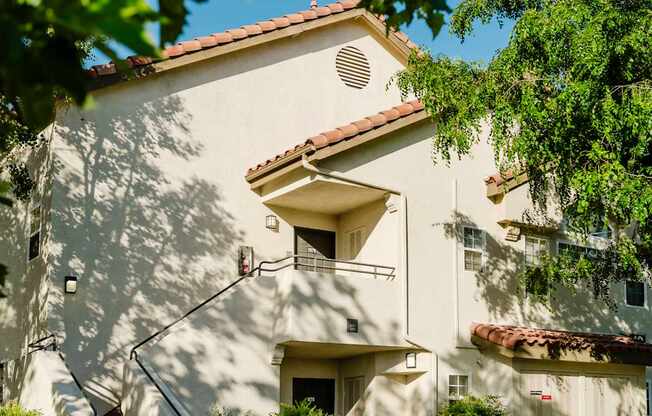 A white building with a red tile roof and a balcony.