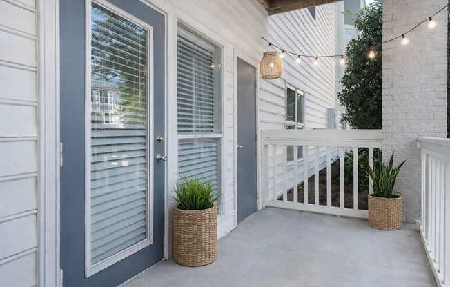 An outdoor private balcony with blue doors, decorated with plants and outdoor lights