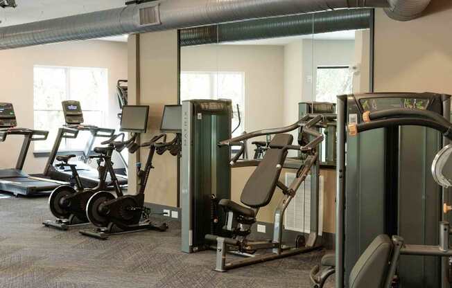 A gym with a variety of exercise equipment including treadmills, stationary bikes, and weight machines.