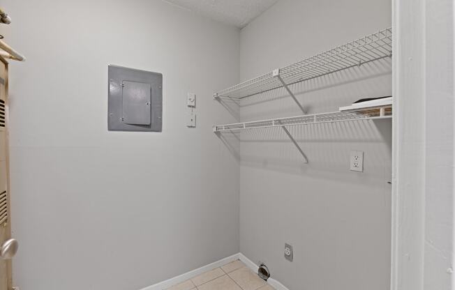a white room with a white closet and a white shelf on the wall