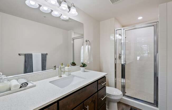 bathroom with large mirror, walk in shower, granite countertops and extra vanity space