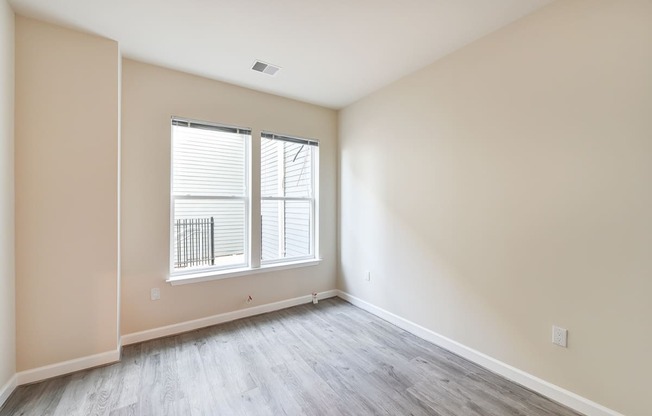 vacant bedroom with hardwood flooring and large windows at city view apartments in washington dc
