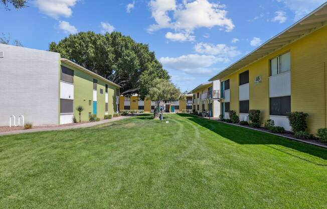 a row of yellow and white houses with grass and trees