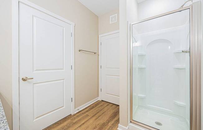 A white door is on the left and a glass shower door is on the right.