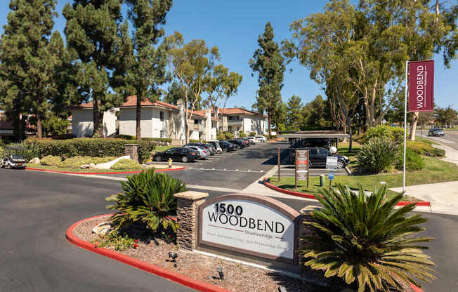 The image shows a sign for Woodbend in front of a parking lot.