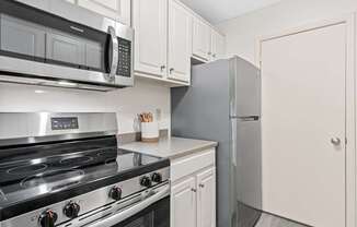 A kitchen with a stove, microwave, and refrigerator.