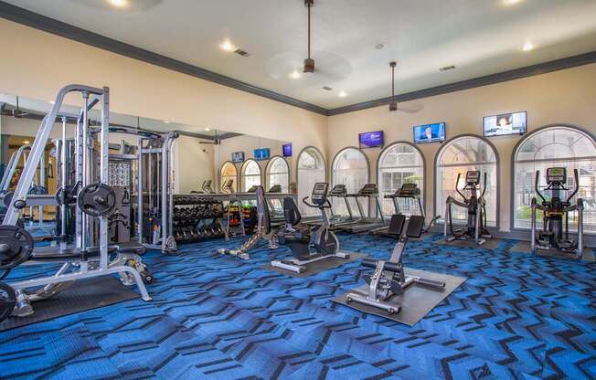 A gym with a variety of equipment including treadmills, weights, and exercise machines.