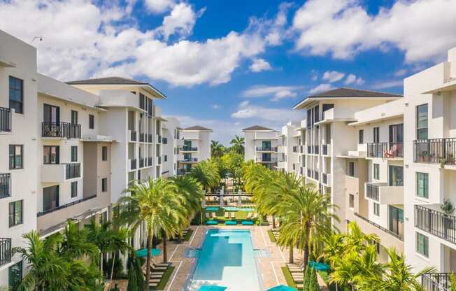 an aerial view of an apartment complex with a pool and palm trees