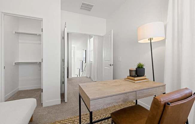 A room with a desk, chair, and a lamp.