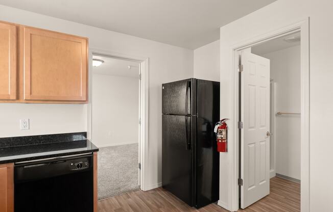 a kitchen with a black refrigerator and a door to a hallway