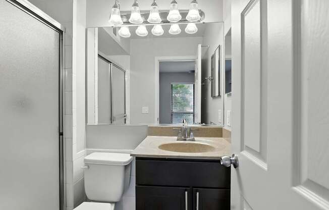 A bathroom with a toilet, sink, and mirror.