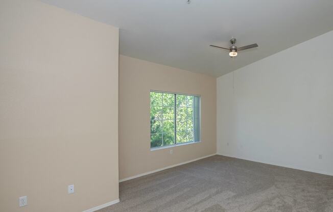 an empty room with a window and a ceiling fan