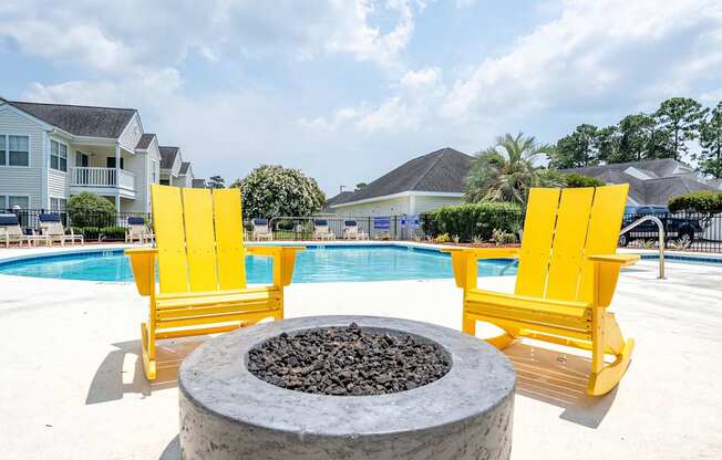 Two yellow chairs are placed on a patio next to a fire pit.