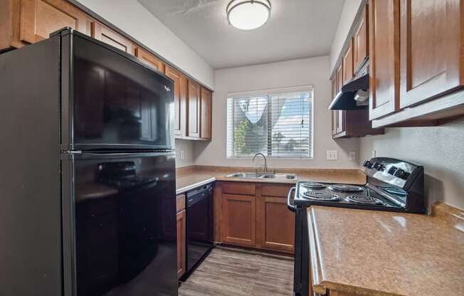 an updated kitchen with black appliances and wood cabinets