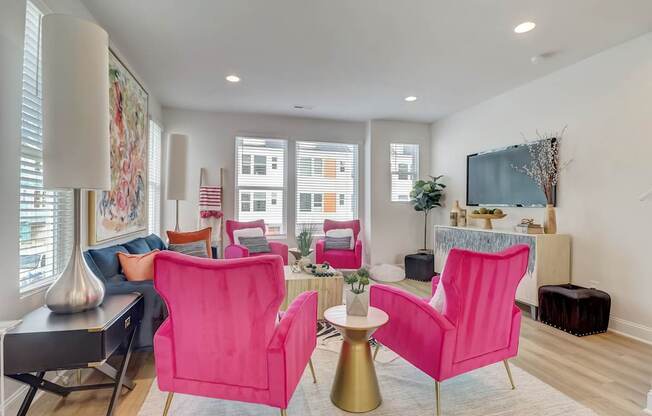 A living room with a pink chair and a grey sofa.