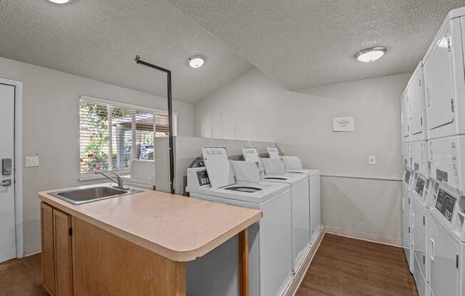 A laundry room with a counter and washers and dryers.