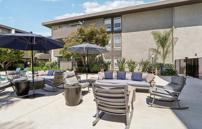 a patio with chairs and tables and umbrellas in front of a building