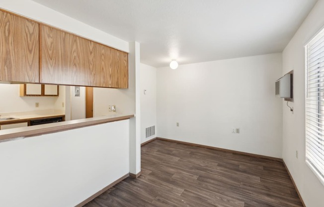 an empty living room and kitchen with wood flooring and a window