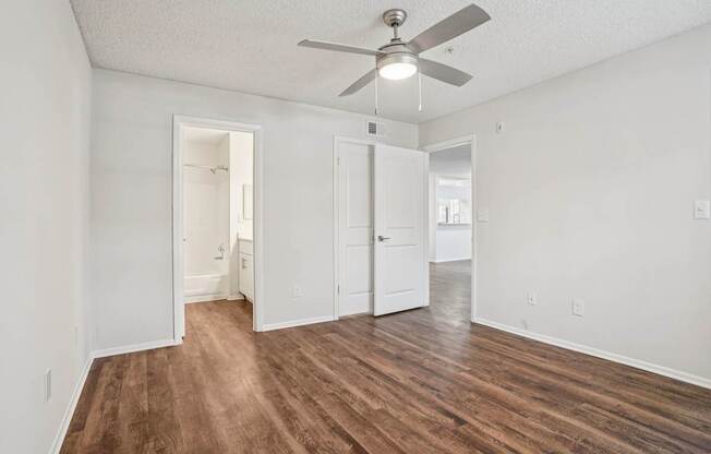 A room with a ceiling fan and wood flooring.