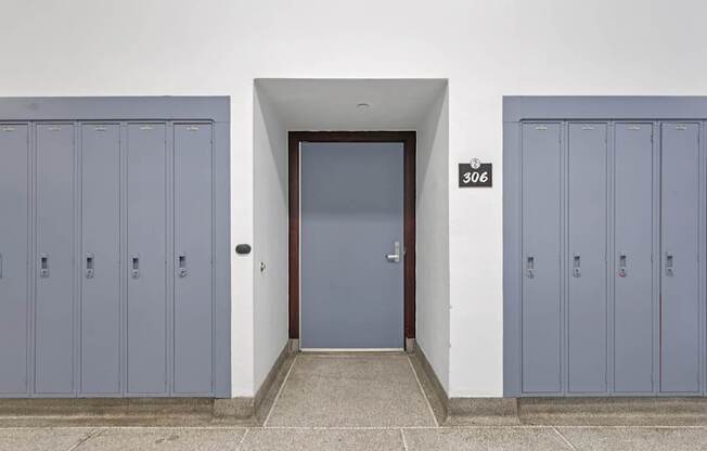 A set of blue lockers are on either side of a door with a number 306 above it.