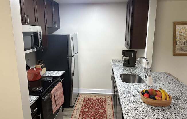 a kitchen with black appliances and granite countertops and a bowl of fruit
