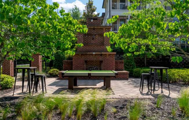 a backyard with a ping pong table and a brick fireplace