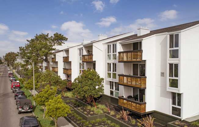 a row of white apartment buildings with balconies and a parking lot