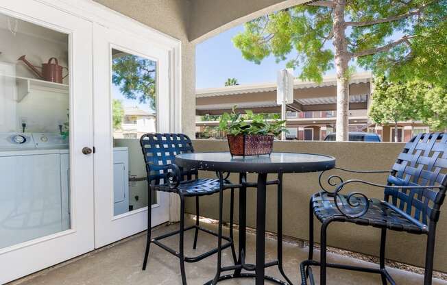A patio with a table and chairs and a view of a building.
