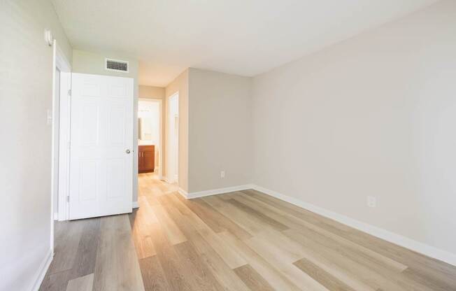 A room with a white door and wooden flooring.