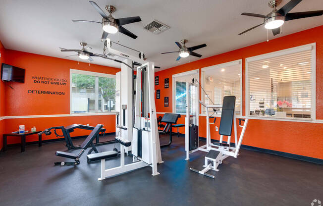 a gym with exercise equipment and ceiling fans