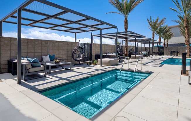 A pool with a glass enclosure and a patio area with a table and chairs.