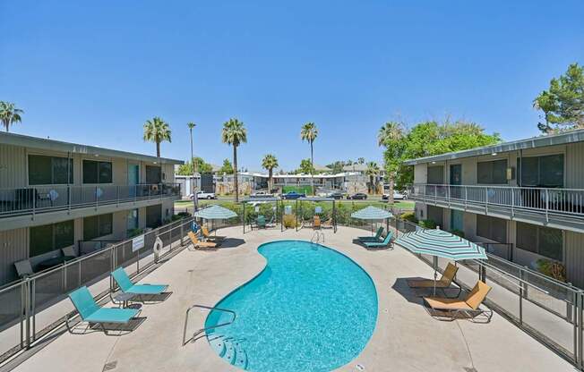 A swimming pool surrounded by lounge chairs and umbrellas.