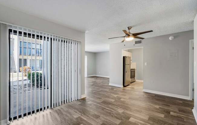 Model living room with ceiling fan, sliding door to patio, and wood flooring at Oasis at Bayside in Largo, FL.