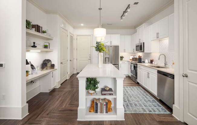 a white kitchen with a white island and stainless steel appliances