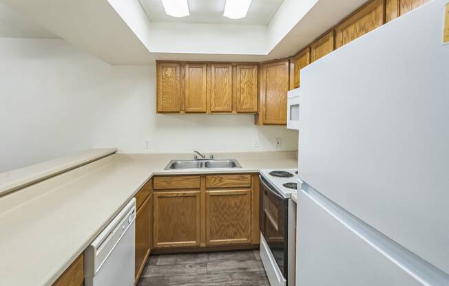 an empty kitchen with white appliances and wooden cabinets