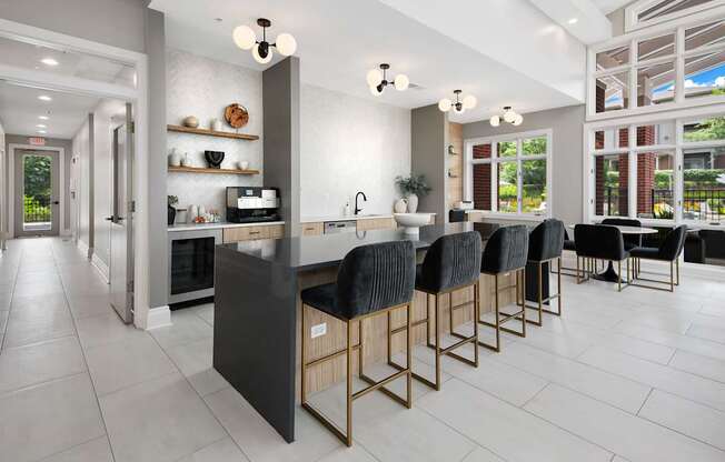 A modern kitchen with a long island and black chairs.